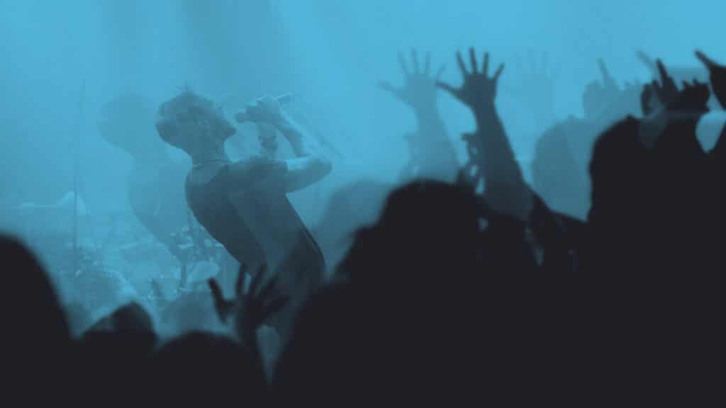 Man on stage singing with blue overlay.